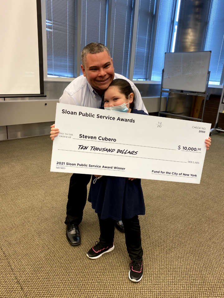 Steven Cubero’s daughter helps him hold up the giant check.