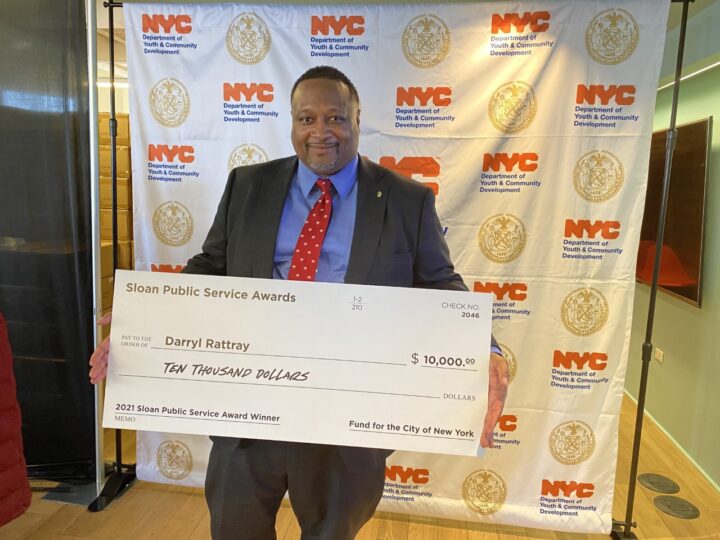 Darryl Rattray holding up giant check at NYC DYCD